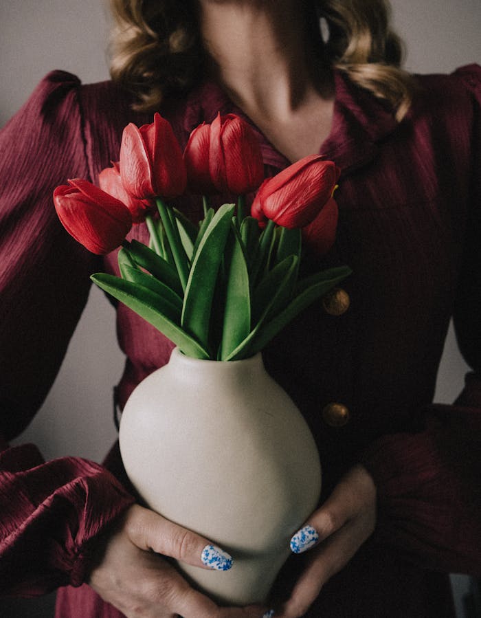 elegant-woman-holding-vase-of-red-tulips-31617254